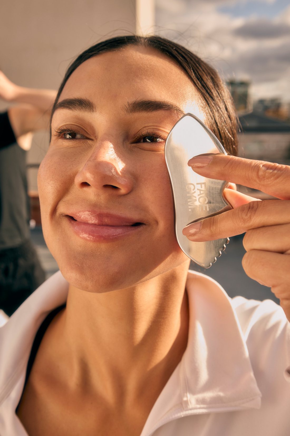 Close-up of Maria using a steel gua sha on her cheek