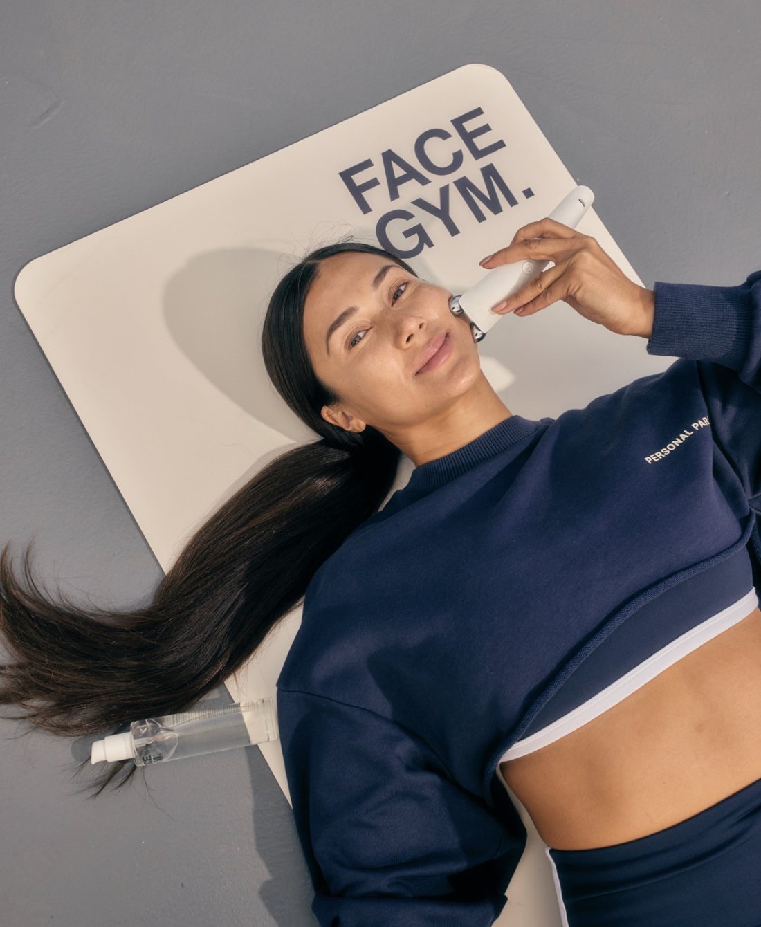Maria lying on a mat using a facial sculpting tool