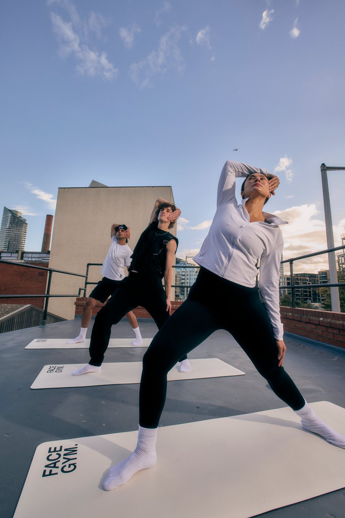 Maria and two others stretching on mats on a rooftop